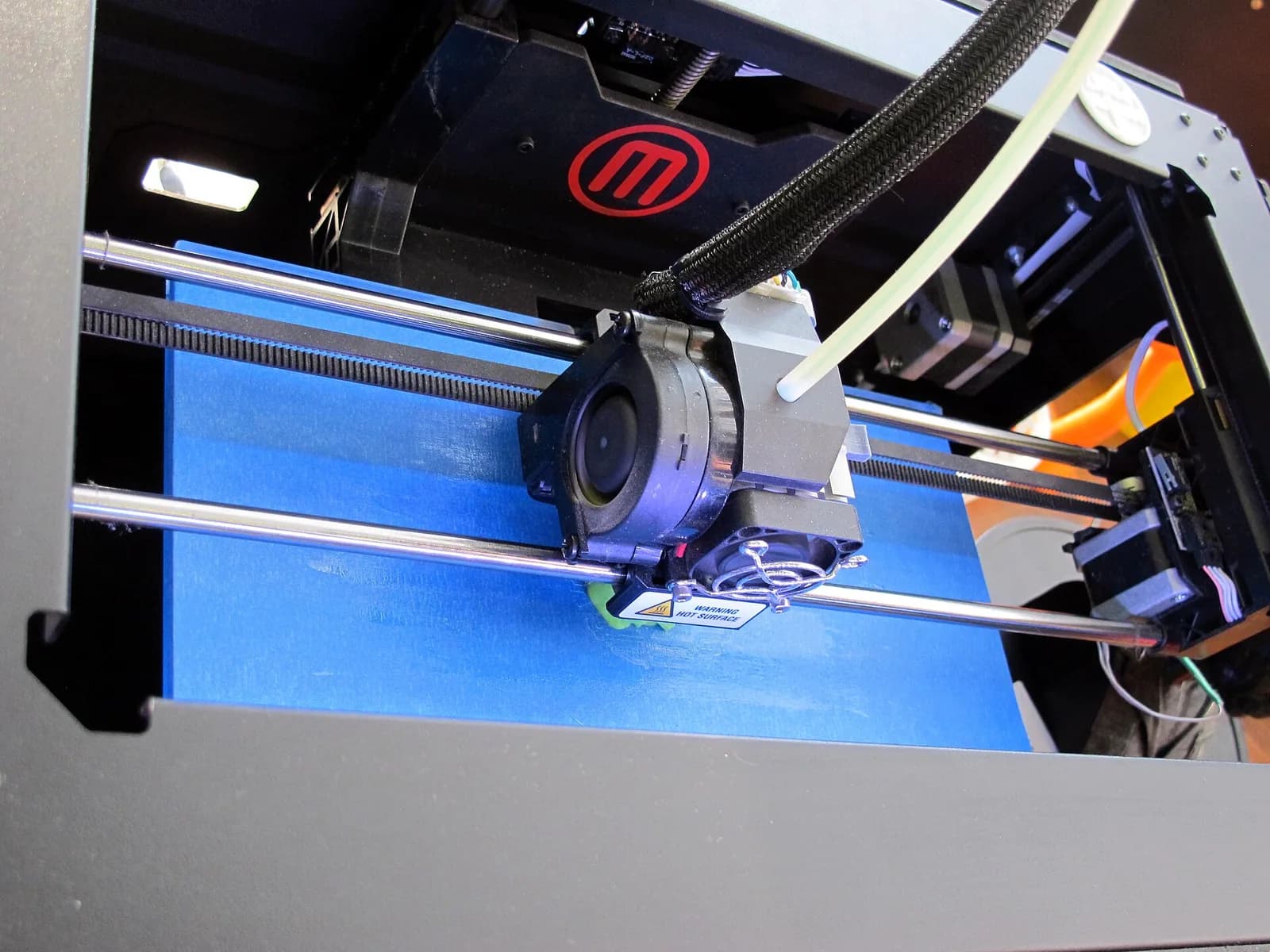 Close view of an FDM 3D printer extruder and print bed